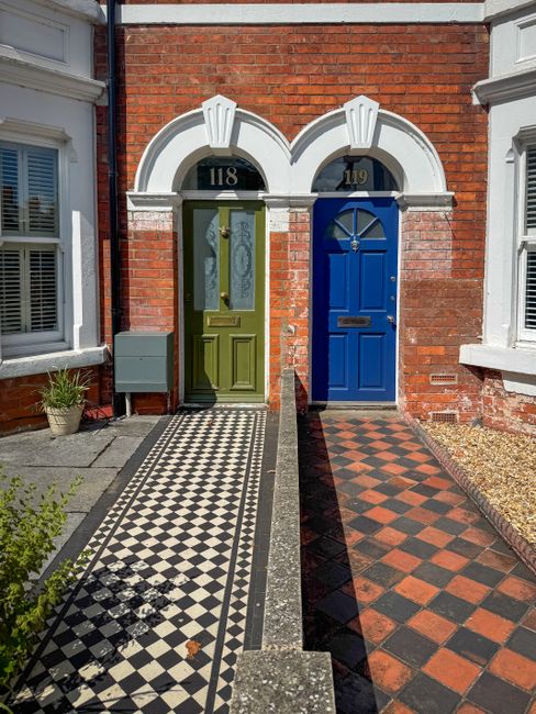 This image depicts the front exterior of a traditional Victorian terrace house during a home relocation or moving process. The house features a red brick facade with white decorative brickwork and a p
